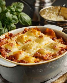 a casserole dish with meat and cheese in it sitting on a table next to other dishes