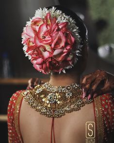 the back of a woman's head with flowers in her hair and jewelry on it