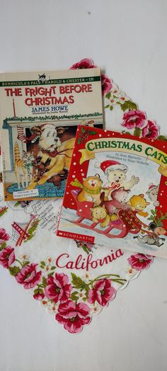 three children's books are laying on top of a tablecloth with pink flowers