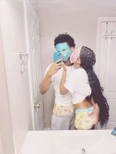 a man and woman taking a selfie in front of a mirror with their face masks on