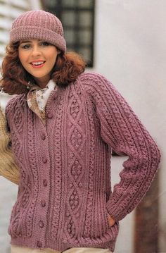 a woman wearing a purple cabled sweater and hat with her hands on her hips