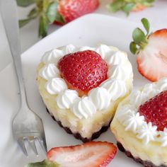 two desserts on a plate with strawberries next to them and a fork in the foreground