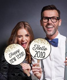 a man and woman holding happy new year's signs in front of their faces