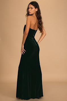 a woman in a long black dress with her back turned to the camera and looking down