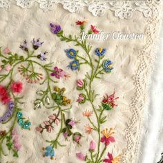 an embroidered piece of cloth with flowers on it and lace trimmings around the edges