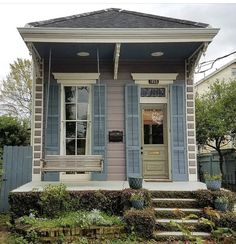 a small house with blue shutters and steps leading to the front door is shown