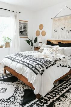 a white bedroom with black and white decor on the walls, rugs and bedding