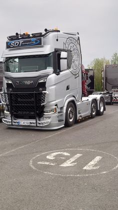 a large semi truck parked in a parking lot next to a trailer with the word so far on it's side