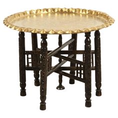 an ornately decorated table with gold leaf accents on the top and bottom, against a white background