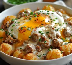 a white bowl filled with tater tots covered in an egg and cheese sauce