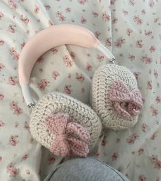 a pair of crocheted ear muffs laying on top of a bed next to a pink headphone