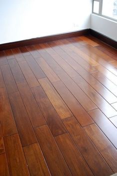 an empty room with hard wood floors and windows in the corner is seen from across the room