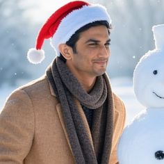 a man standing next to a snowman wearing a santa hat