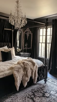 a bedroom with black walls, white bedding and a chandelier hanging from the ceiling