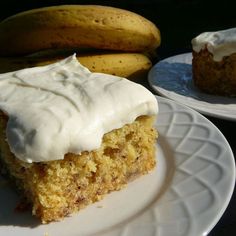 a piece of cake with white frosting sitting on a plate next to some bananas