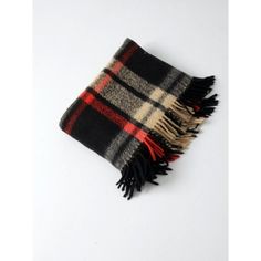 a black and white plaid scarf with fringes on the ends is laying flat against a white background