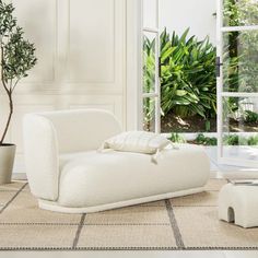 a white couch sitting on top of a tiled floor next to a potted plant