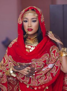 a woman dressed in red and gold is posing for the camera with her hands on her chest