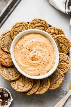 a bowl of peanut butter surrounded by cookies on a plate with dipping sauce in the middle