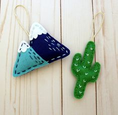 two felt ornaments are sitting on a wooden surface next to a cactus ornament