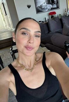 a woman making a funny face while sitting in front of a couch with her hand on her hip