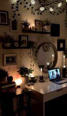 a laptop computer sitting on top of a desk next to a wall filled with pictures