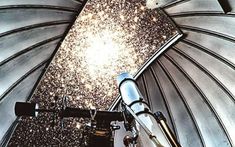 a telescope is sitting on top of a metal structure with stars in the sky above it