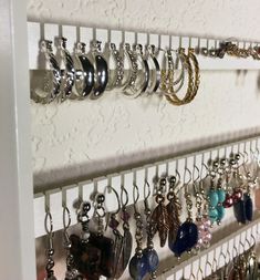 a wall mounted jewelry rack with several pairs of earrings hanging from it's sides