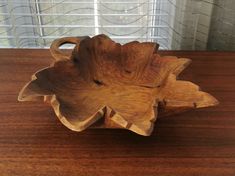 a wooden bowl sitting on top of a wooden table next to a glass wall window