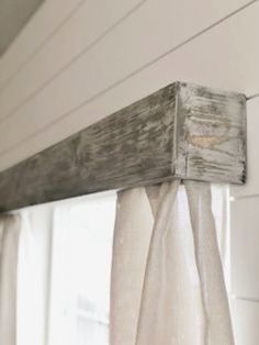 an old window frame is hanging on the side of a house with curtains pulled back