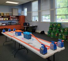 a long table with blue and orange plastic containers on it in a room filled with toys