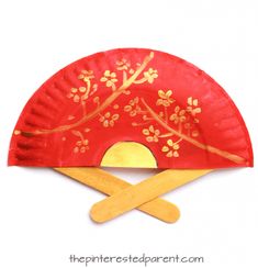 a red paper plate with gold designs on it and two wooden sticks sticking out of it