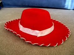 a red hat sitting on top of a floor next to a blue pillow with white trim