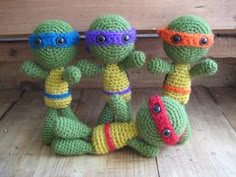 three crocheted teenage mutant dolls sitting next to each other on a wooden surface