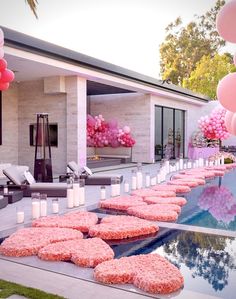 an outdoor party with donuts and candles on the side of the pool, decorated with pink balloons