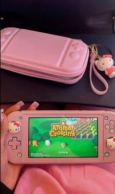 a pink nintendo wii game system with hello kitty keychain and case on it