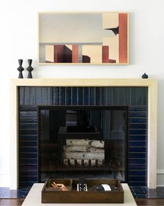 a living room with a fire place and painting on the wall above it's mantle