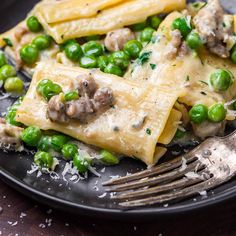 a black plate topped with pasta and peas