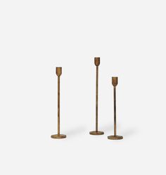 three brass candlesticks are standing in the middle of each other on a white background