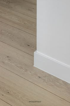 the corner of an empty room with wood flooring