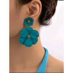 a woman wearing blue earrings with flowers on it's back drops from her ear