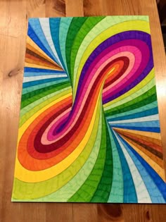 a multicolored piece of art sitting on top of a wooden table