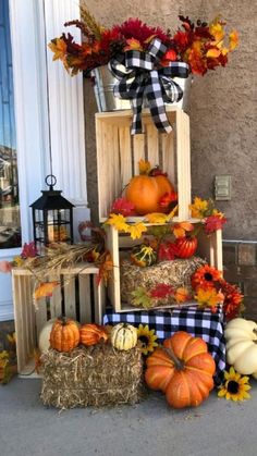 pumpkins, hay bales and sunflowers are arranged in front of a house