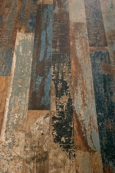 an old, worn and stained wooden floor is shown in this close up photo with the colors of rusted paint on it