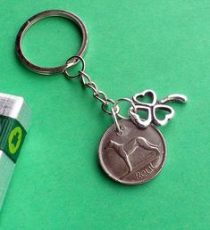 a silver keychain with a one pound coin attached to it on a green surface