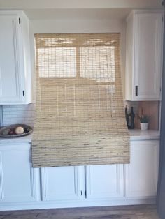 a kitchen with white cabinets and bamboo blinds