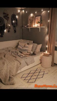 a bed with blankets and pillows in a room that has lights on the wall above it