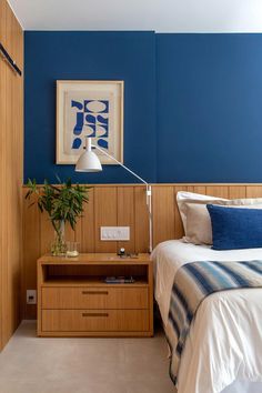 a bed room with a neatly made bed next to a night stand and a plant