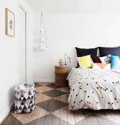 a bed sitting in a bedroom next to a window with lots of pillows on top of it