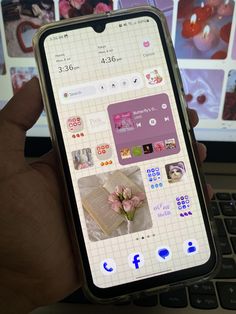 someone is holding their cell phone in front of a laptop computer with pictures on the screen